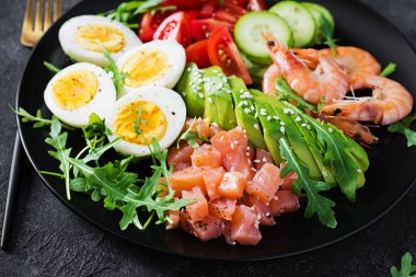 Ketogenik diyet kahvaltısı. Haşlanmış karides, karides, domates, salatalık, roka, yumurta ve avokado ile tuzlu somon salatası. Keto, öğle yemeği..