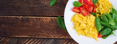 Kahvaltıda. Çilekli yumurta, domates, ıspanak ve mısır. Üst görünüm, afiş, yukarıda