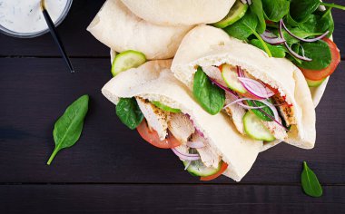 Tavuk, domates, salatalık ve ahşap kaplama ıspanakla doldurulmuş Pita. Orta Doğu mutfağı. Üst görünüm, yukarıda