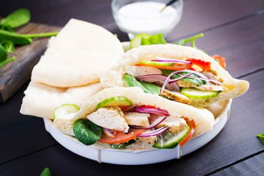 Tavuk, domates, salatalık ve ahşap kaplama ıspanakla doldurulmuş Pita. Orta Doğu mutfağı.