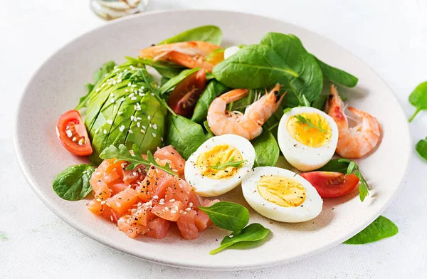 Ketogenik diyet kahvaltısı. Haşlanmış karides, karides, domates, ıspanak, yumurta ve avokado ile tuzlu somon salatası. Keto, öğle yemeği..