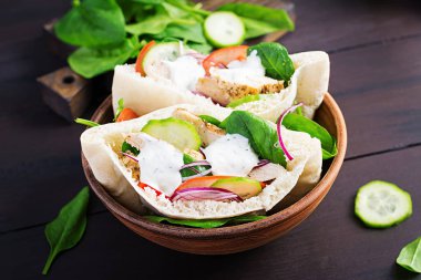 Tavuk, domates, salatalık ve ahşap kaplama ıspanakla doldurulmuş Pita. Orta Doğu mutfağı.