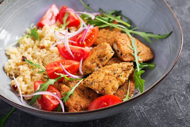Kaynamış bulgur, kızarmış tavuk nugget ve taze domates salatası. Orta Doğu mutfağı.