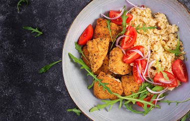 Kaynamış bulgur, kızarmış tavuk nugget ve taze domates salatası. Ortadoğu mutfağı. Üst manzara, düz uzanma