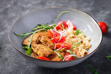 Kaynamış bulgur, kızarmış tavuk nugget ve taze domates salatası. Orta Doğu mutfağı.
