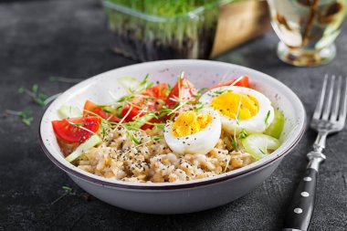 Kahvaltı yulaf lapası haşlanmış yumurta, kiraz domatesleri, kereviz ve mikro yeşillikler. Sağlıklı dengeli yiyecekler.