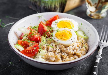 Kahvaltı yulaf lapası haşlanmış yumurta, kiraz domatesleri, kereviz ve mikro yeşillikler. Sağlıklı dengeli yiyecekler.