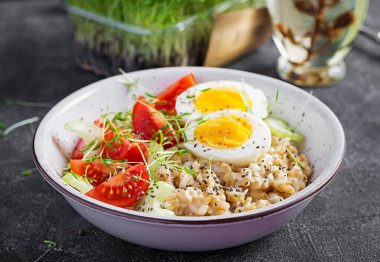 Kahvaltı yulaf lapası haşlanmış yumurta, kiraz domatesleri, kereviz ve mikro yeşillikler. Sağlıklı dengeli yiyecekler.