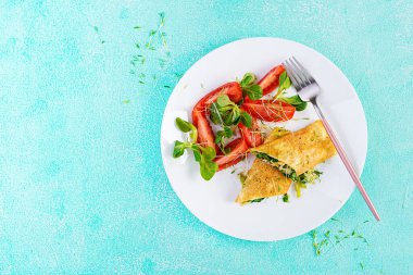 Omlet tabakta yuvarlanıyor. Ev yapımı omlet ve doğranmış sebze. Sağlıklı düşük karbonhidrat tarifi. Üst görünüm, yukarıda