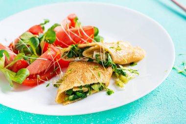 Omlet tabakta yuvarlanıyor. Ev yapımı omlet ve doğranmış sebze. Sağlıklı düşük karbonhidrat tarifi.