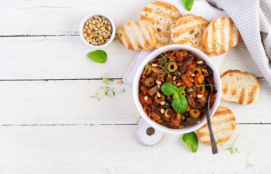 Geleneksel İtalyan Caponata ve tahta beyaz bir masada tost. Sicilya caponata 'sı. Üstten, üstten, düz.