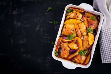 Fırında tavuk butları. Fırında pişmiş tavuğun iştah açıcı dilimleri, kırmızı soğan ve portakallı fırın kabında. Üst görünüm, alanı kopyala