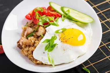 Nasi Goreng. Koyu arkaplanda kızarmış Endonezya tavuğu. Nasi Goreng pilav, tavuk eti, soğan, yumurta ve sebzeli Endonezya mutfağı..
