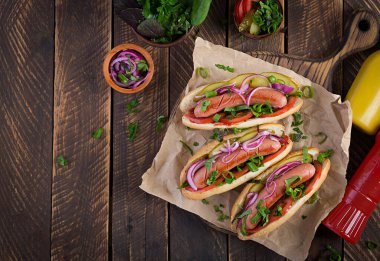 Turşulu sosisli, domates ve marullu ahşap arka planda. Hotdog, Amerikan mutfağı. Üst görünüm, yukarıda, boşluğu kopyala