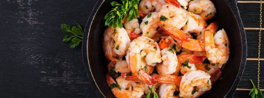 Kızarmış karides. Limon, maydanoz ve sarımsaklı tavada kızarmış karides. Üst görünüm, afiş