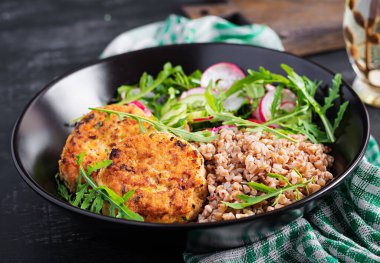 Sağlıklı bir akşam yemeği. Karabuğday lapası, kızarmış tavuk pirzolası ve taze sebze salatası, salatalık ve turp..