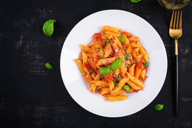 Klasik İtalyan usulü makarna penne alla arrabiata fesleğen ve taze rendelenmiş parmesan peyniri. Acı soslu arrabbiata soslu makarna. Üst görünüm, yukarıda, boşluğu kopyala