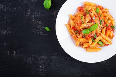 Klasik İtalyan usulü makarna penne alla arrabiata fesleğen ve taze rendelenmiş parmesan peyniri. Acı soslu arrabbiata soslu makarna. Üst görünüm, yukarıda, boşluğu kopyala