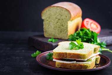 Ispanaklı ekmek ve peynirli sandviç, domates ve bitkilerle. Sağlıklı öğle yemeği.