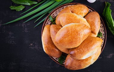 Geleneksel Ukrayna turtaları, yumurtalı, yeşil soğanlı, koyu arkaplanlı. Rus piroshki, ev yapımı fırında köfte. Üst görünüm, yukarıda, boşluğu kopyala