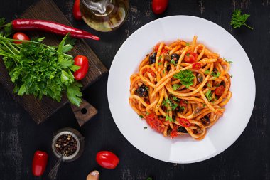 Spagetti alla puttanesca - domatesli İtalyan makarna yemeği, siyah zeytin, kapari, ançüez ve maydanoz. Üst manzara, düz uzanma