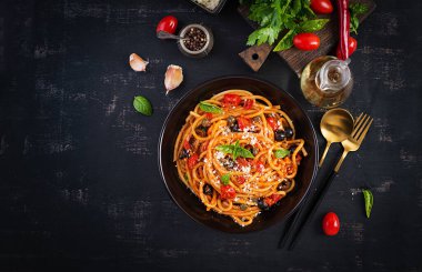 Spagetti alla puttanesca - domatesli İtalyan makarna tabağı, siyah zeytin, kapari, ançüez ve fesleğen. Üst manzara, düz uzanma