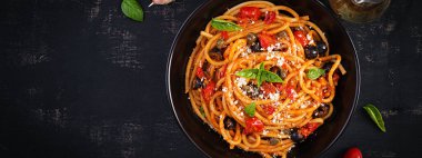 Spagetti alla puttanesca - domatesli İtalyan makarna tabağı, siyah zeytin, kapari, ançüez ve fesleğen. Üst manzara, düz uzanma