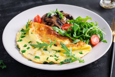 Peynirli omlet, yeşil otlar ve tabakta kızarmış mantar. Frittata - İtalyan omleti