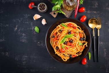 Spagetti alla puttanesca - domatesli İtalyan makarna tabağı, siyah zeytin, kapari, ançüez ve fesleğen. Üst manzara, düz uzanma