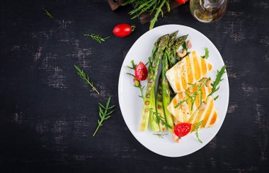 Izgara halloumi peynirli salata, domatesli ve koyu arkaplanda kuşkonmaz. Sağlıklı vejetaryen yemekleri. Üst görünüm, yukarıda