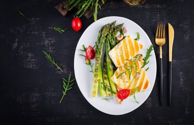 Izgara halloumi peynirli salata, domatesli ve koyu arkaplanda kuşkonmaz. Sağlıklı vejetaryen yemekleri. Üst görünüm, yukarıda