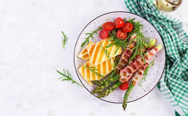 Izgara halloumi peynirli salata, domatesli ve pastırmalı kuşkonmaz. Sağlıklı yiyecekler. Üst manzara, düz uzanma