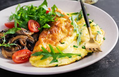 Peynirli omlet, yeşil otlar ve tabakta kızarmış mantar. Frittata - İtalyan omleti