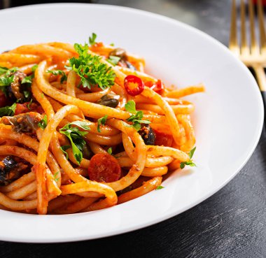 Spagetti alla puttanesca - domatesli İtalyan makarna tabağı, siyah zeytin, kapari, ançüez ve maydanoz.