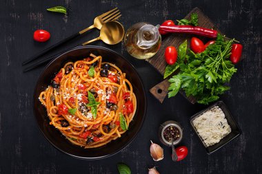 Spagetti alla puttanesca - domatesli İtalyan makarna tabağı, siyah zeytin, kapari, ançüez ve fesleğen. Üst manzara, düz uzanma