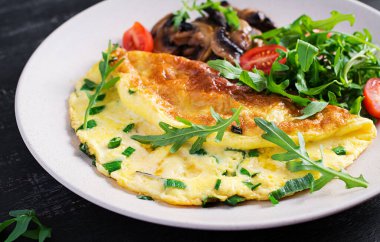 Peynirli omlet, yeşil otlar ve tabakta kızarmış mantar. Frittata - İtalyan omleti