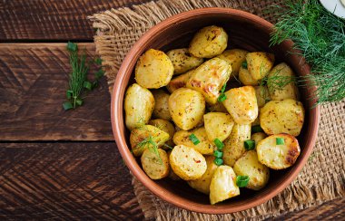 Ahşap masadaki bir kasede fırında patates dilimleri. Lezzetli yemek. Üst görünüm, genel görünüm