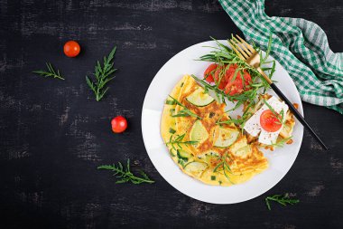 Kabaklı omlet, yeşil otlar ve tabakta peynirli sandviç. Frittata - İtalyan omleti. Üst görünüm, yukarıda, boşluğu kopyala