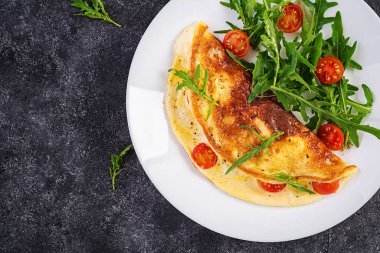 Kahvaltıda. Beyaz tabakta domatesli omlet, peynir ve salata. Frittata - İtalyan omleti. Üst görünüm