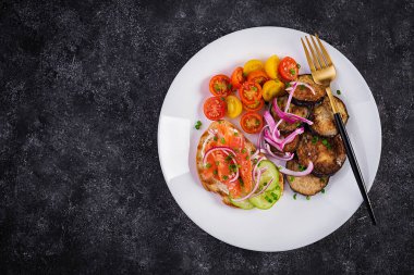Lezzetli brunch somon ekmekli krem peynirli sandviçler ve roka, koyu arkaplanda domates salatası. Üst görünüm, yukarıda