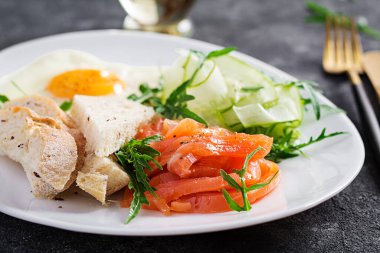 Diyet kahvaltı. Sebzeli tuzlu somon salatası, salatalık, kızarmış yumurta ve ekmek..