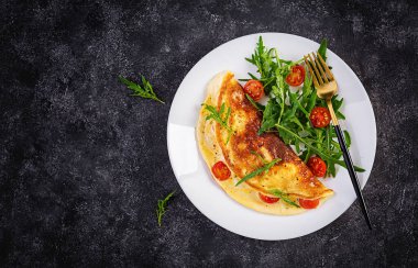 Kahvaltıda. Beyaz tabakta domatesli omlet, peynir ve salata. Frittata - İtalyan omleti. Üst görünüm