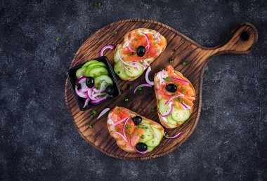 Krem peynirli tost, füme somon, salatalık ve kırmızı soğan. Sandviç aç. Sağlıklı bakım, süper gıda konsepti. Üst görünüm, genel görünüm