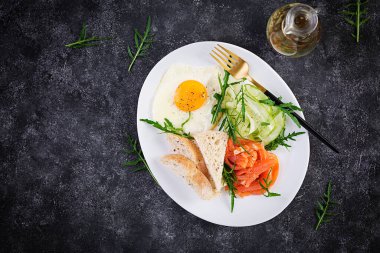 Diyet kahvaltı. Sebzeli tuzlu somon salatası, salatalık, kızarmış yumurta ve ekmek. Üst görünüm, genel görünüm