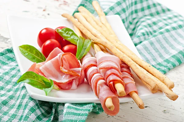 Grissini bread sticks with ham, tomato and basil — Stock Photo, Image