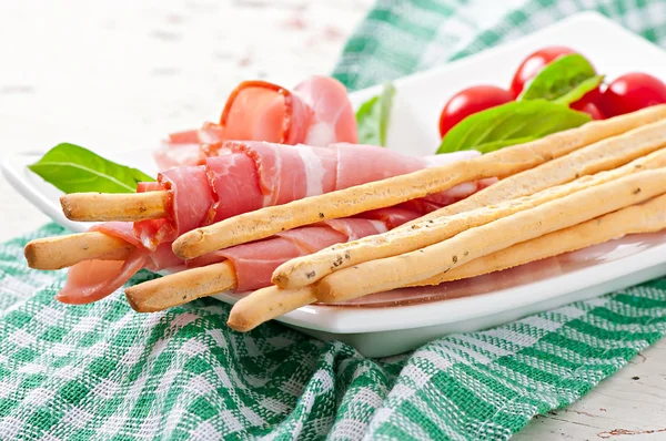 Grissini bread sticks with ham, tomato and basil — Stock Photo, Image