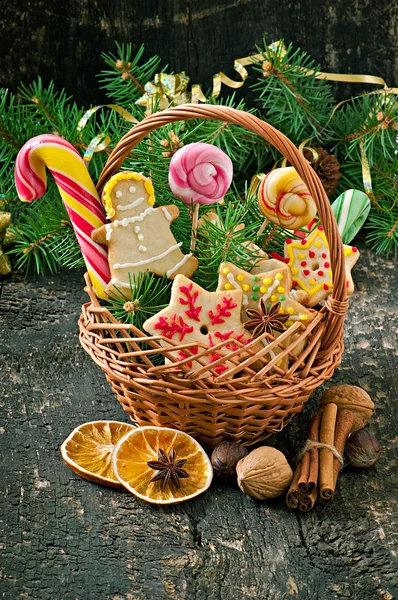 Biscoitos de gengibre de Natal e pirulitos em uma cesta no fundo de madeira velha — Fotografia de Stock