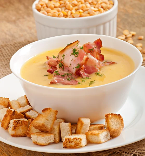 Cream soup of peas with fried bacon and croutons — Stock Photo, Image