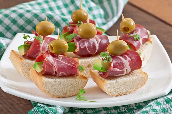 Snack on toast with ham, avocado and olives