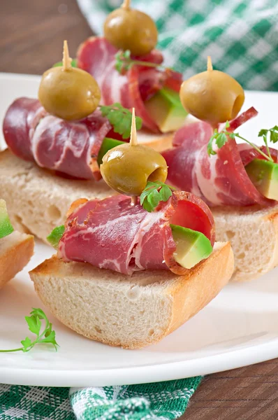 Snack on toast with ham, avocado and olives — Stock Photo, Image